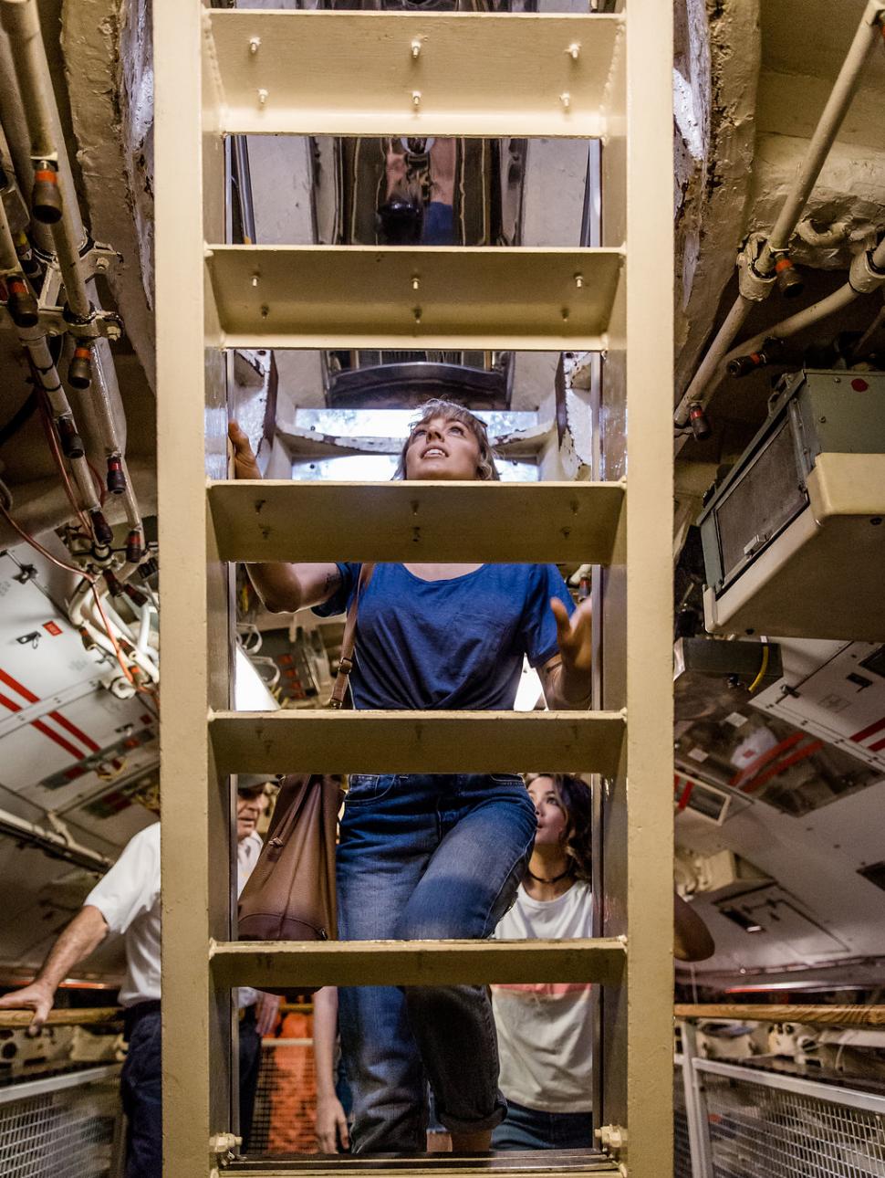 lady climbing ladder inside a submarine