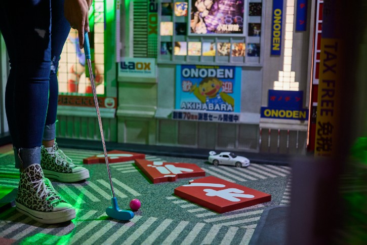 HoleLegs standing with golf putter about to hit a golf ball at Holey Moley 