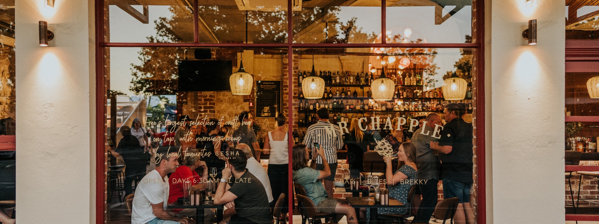 people inside warmly lit bar enjoying food, drinks and chats