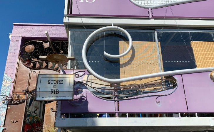 Bright pink building with sculptural, industrial shapes and sign saying STORE AT FIB