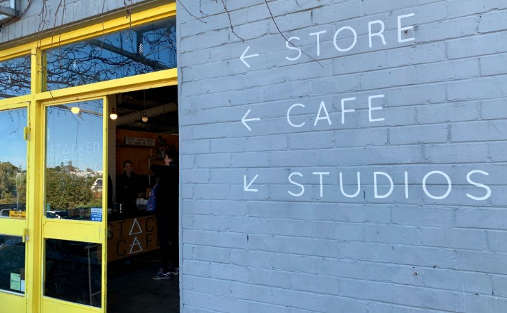 bright yellow door feame next to cool grey wall, painted with directions to STORE, CAFE, STUDIOS