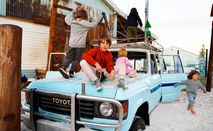 kids play on old blue toyota in giant sandpit playground