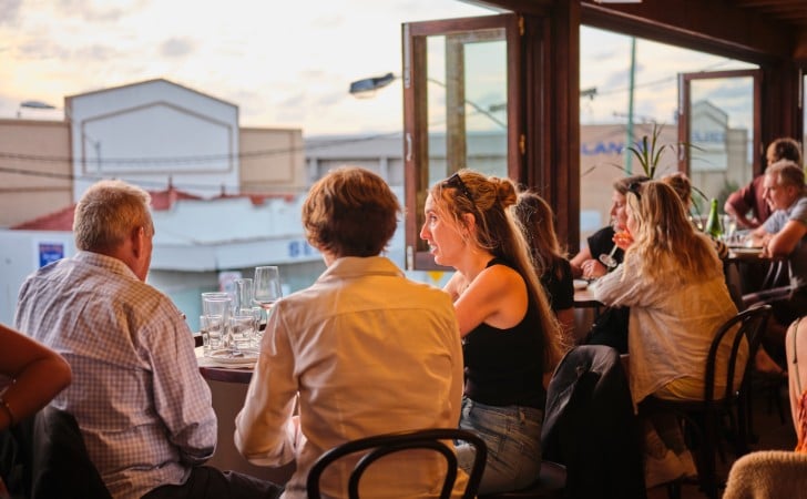 diners chat and look out window of urban rooftop bar