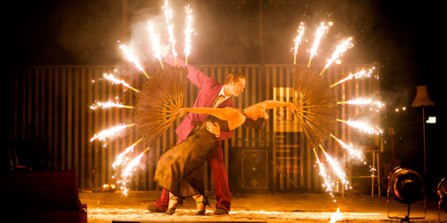 two glamorous dancers poised in a dramatic hold, twirling sparklers