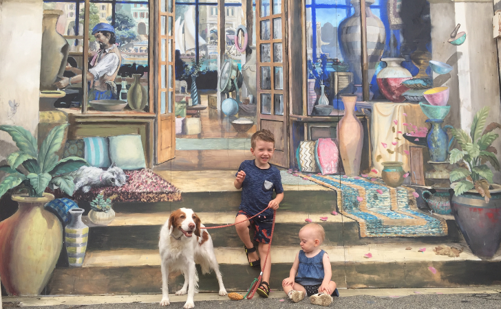 Kids and a dog in front of the tromp l'oeil style mural at East West Design