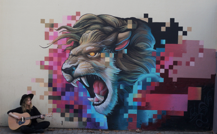 mural of roaring lion near busker playing guitar