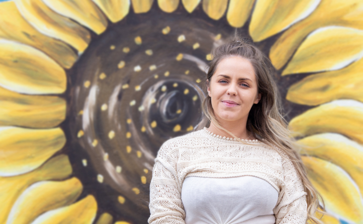 person stands in front of yellow sunflower mural