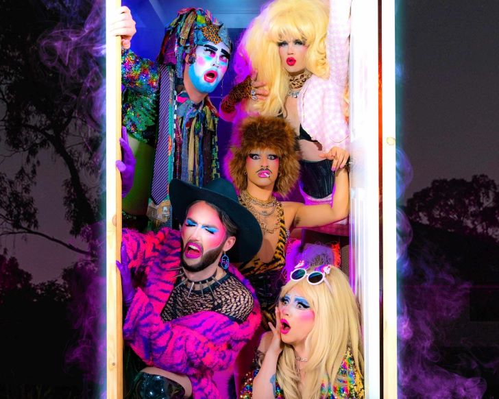 Five cabaret stars dressed in bright costumes open a door.