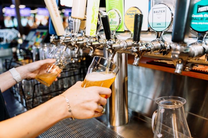 A person pulls two beers from a tap in a pub.