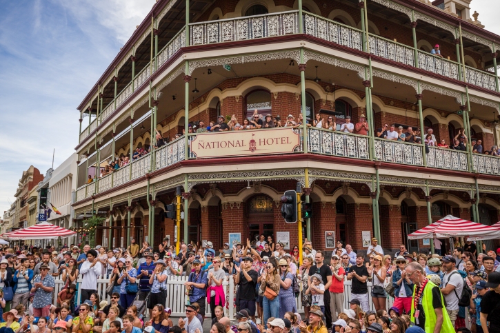 A crowd gathered outside an old multi-storeyed pub watching a busker.