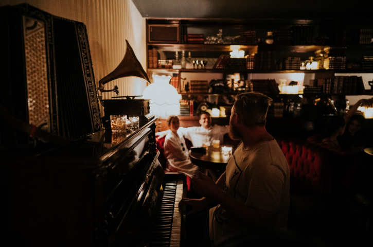 Person playing piano in a dimly lit bar. 
