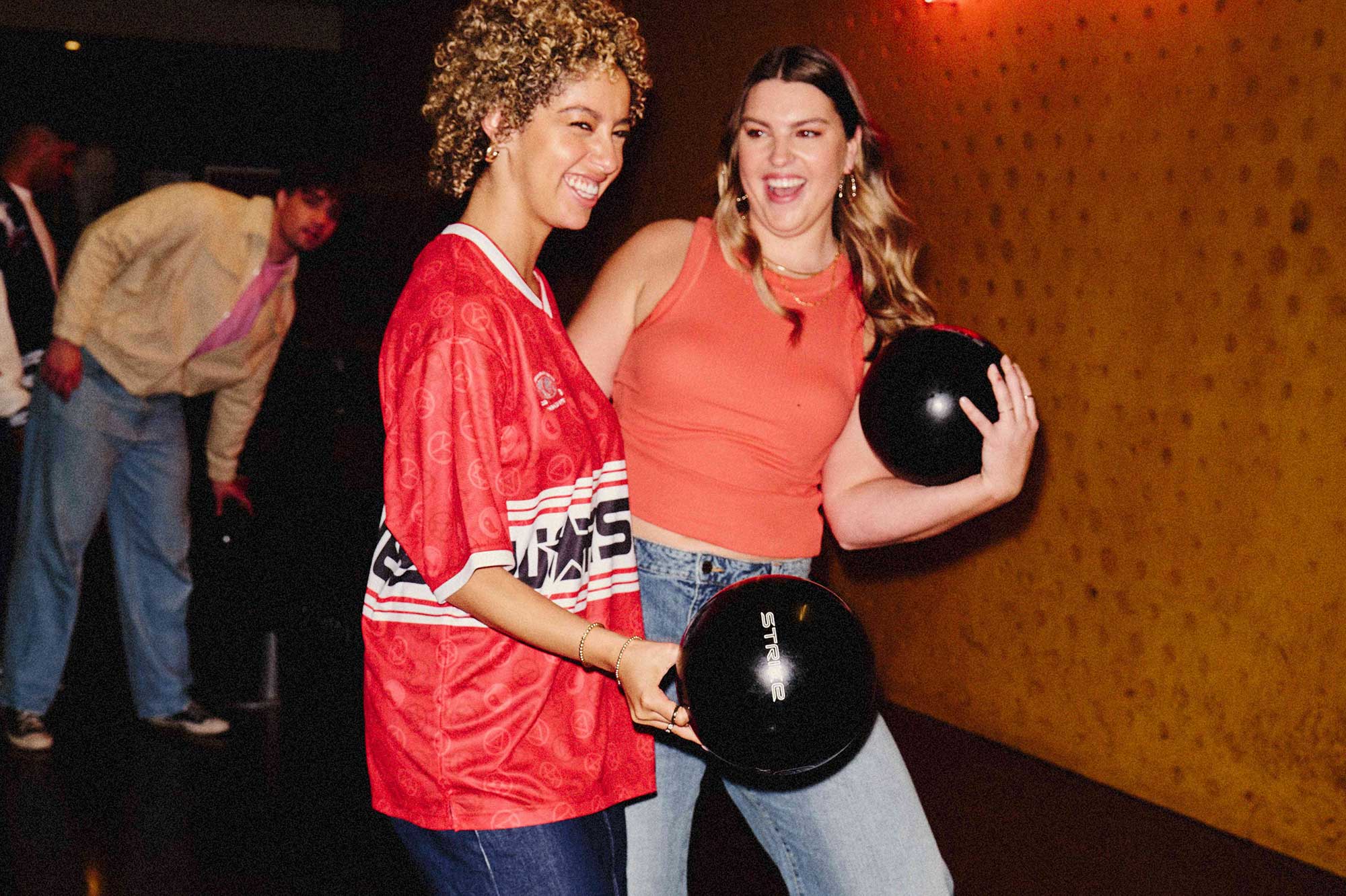 two women holding bowling balls and smiling 