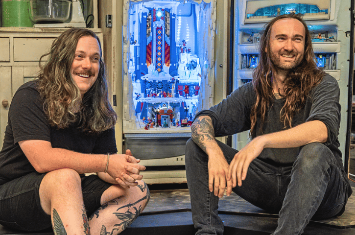 Jackson and Alex from Behind the Builds sitting on a step with big smiles 