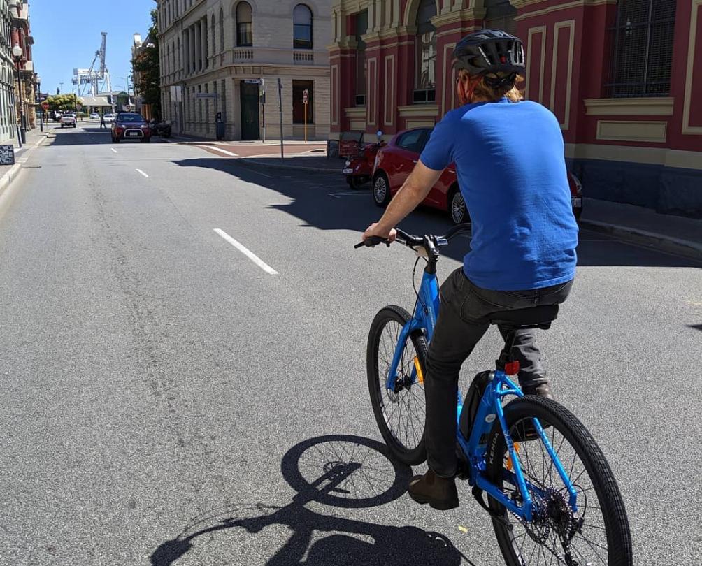 man riding bike down historical street in Fremantle 