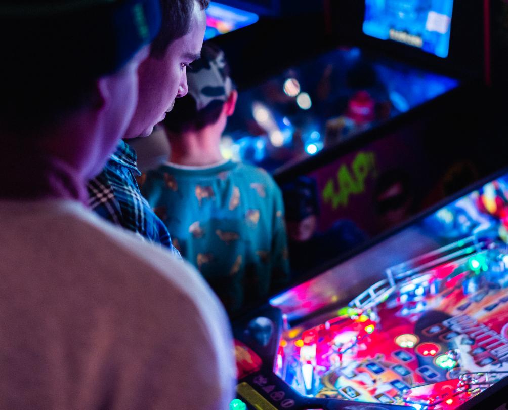 Close up of man playing vintage pinball machine at The Palace Arcade