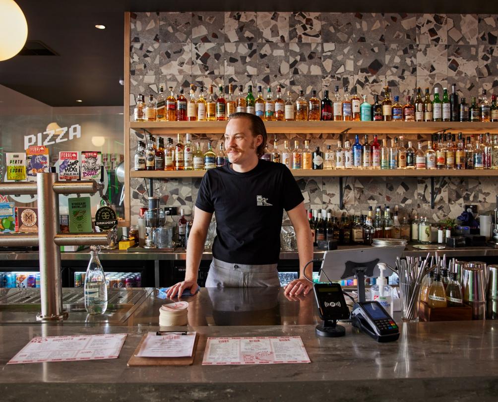 The Palace Arcade - barman behind the bar with menus resting on the top of the bar