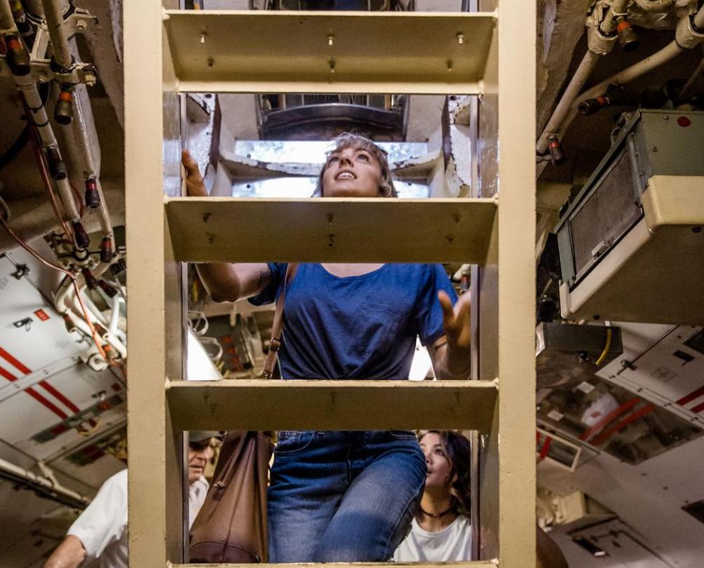 lady climbing ladder inside a submarine