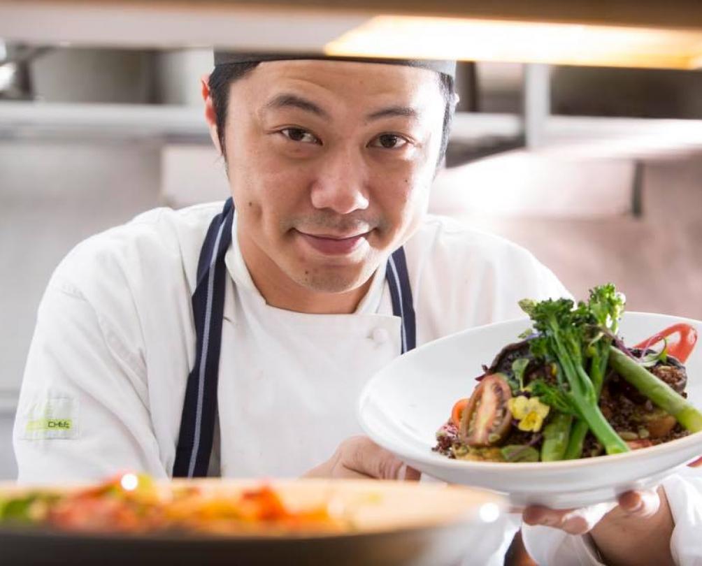 chef in the kitchen holding plates of food. 