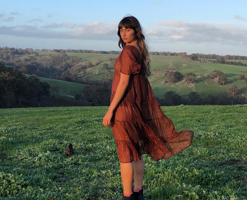 girl in a paddock with dress and boots