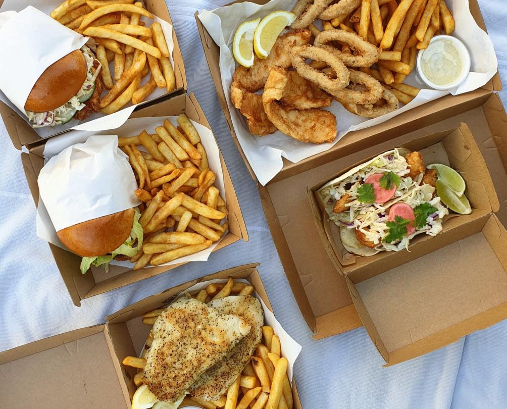 takeaway fish and chips and burgers on a picnic blanket