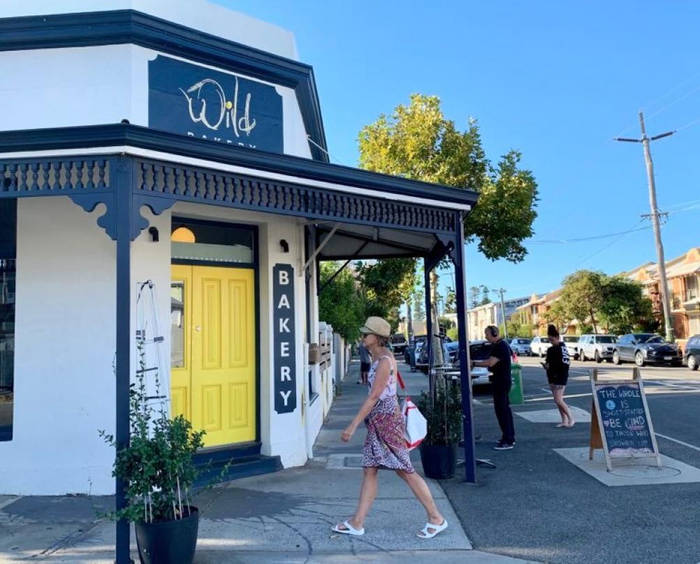 Wild Bakery Person walking in front of the bright yellow front door of Wild Bakery in South Fremantle