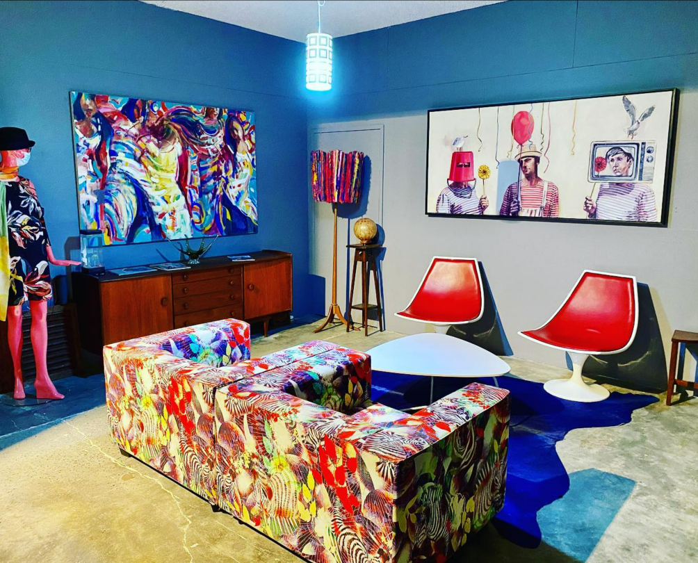 eclectic room with patterned sofa, a fashion manequin, retro furniture and abstract artwork