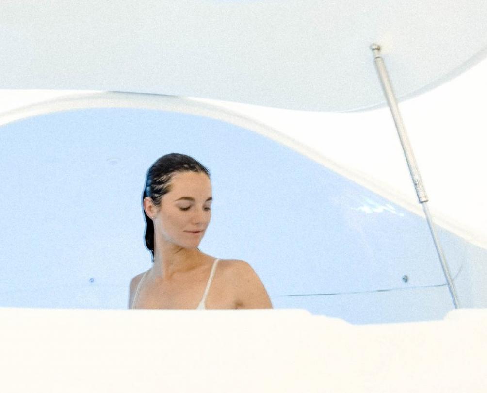 person with wet hair looks relaxed in white float tank