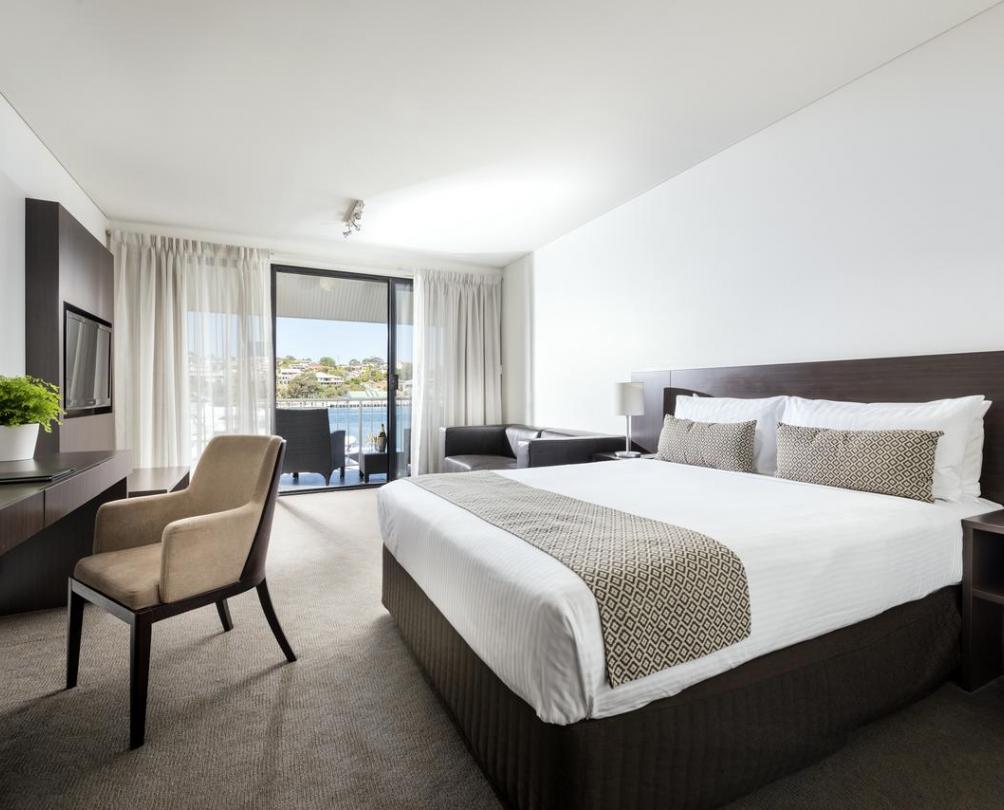 Pier 21 Apartment Hotel, North Fremantle Interior of hotel room - large bed with side table, chair and sliding doors with view out to Swan River