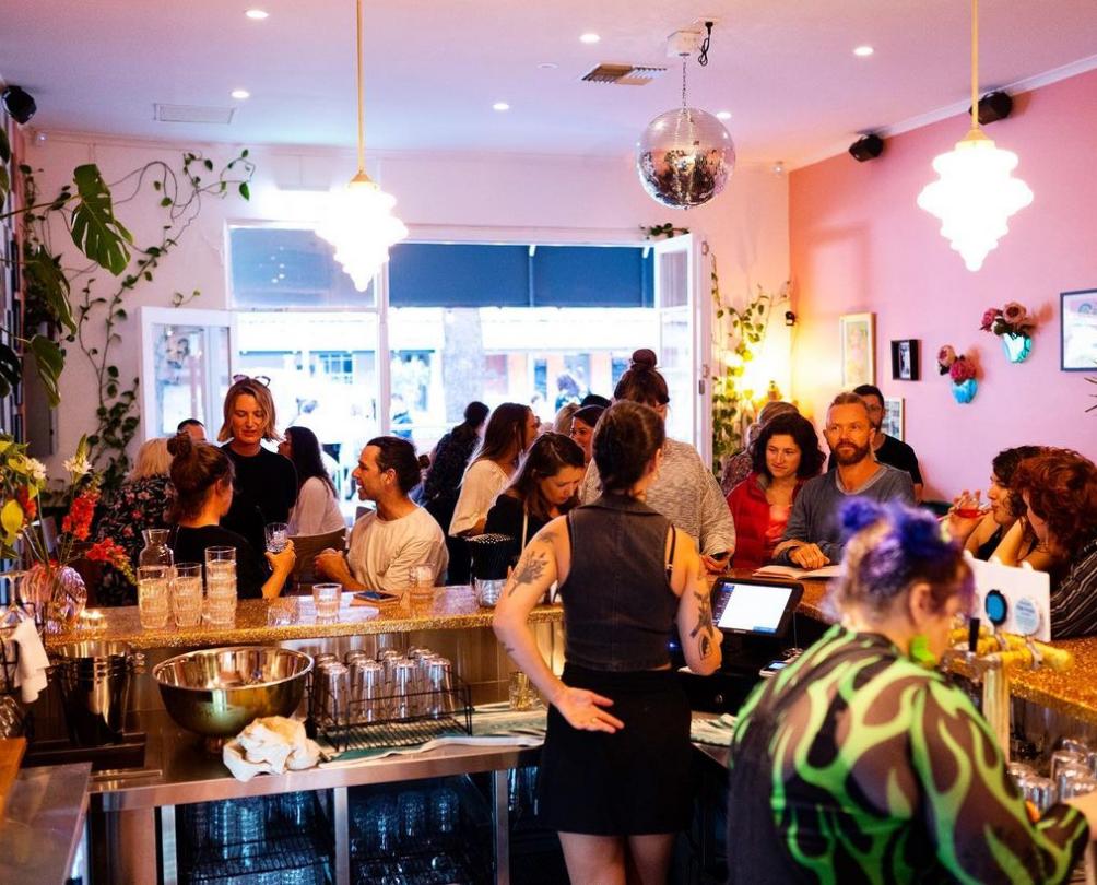 busy pink bar filled with plants and people having fun