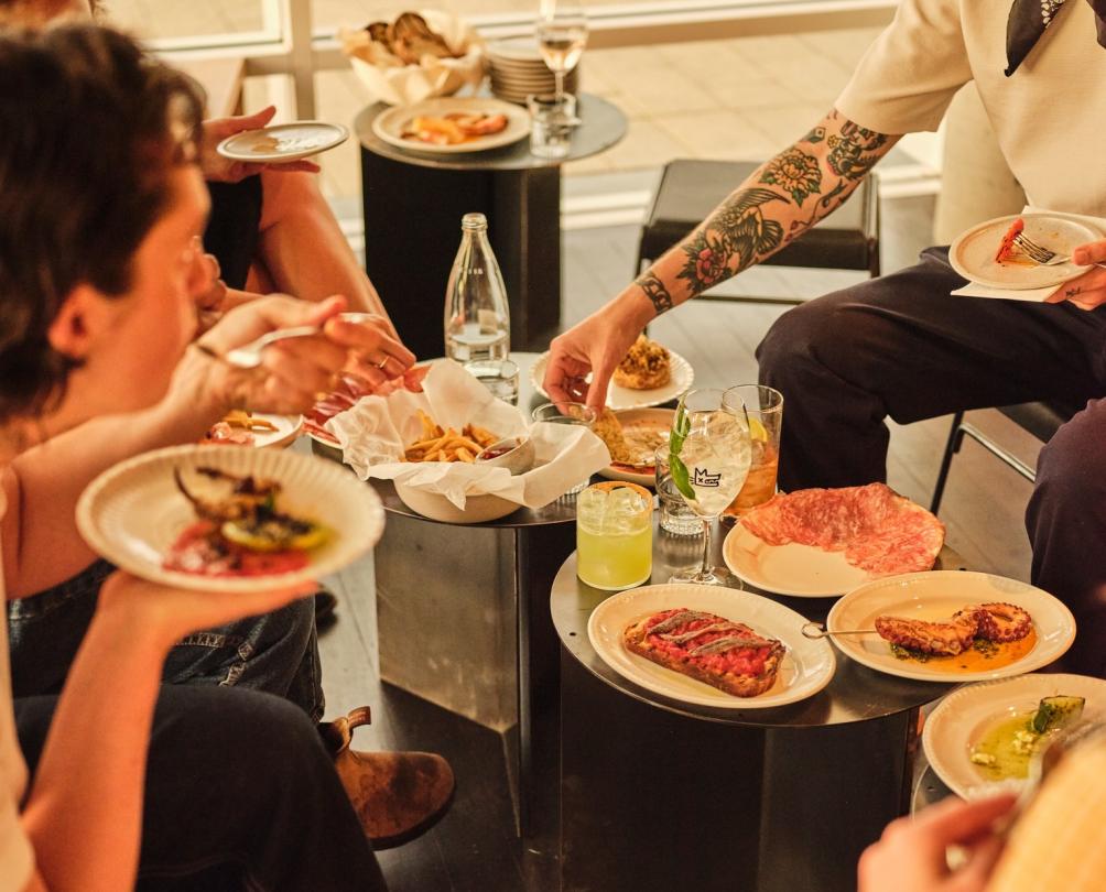 People enjoying plates of food and drinks at Al Lupo