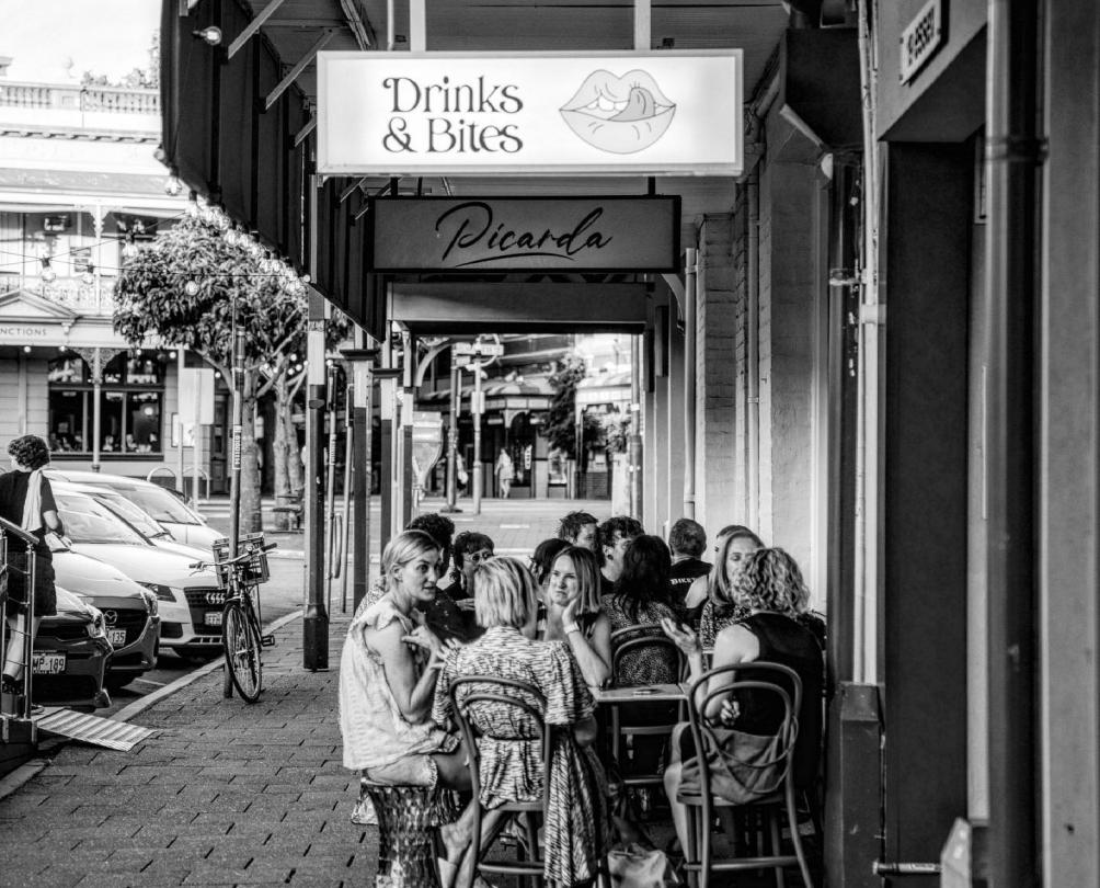 Black and white image of groups of people at tables outside The Flaming Galah