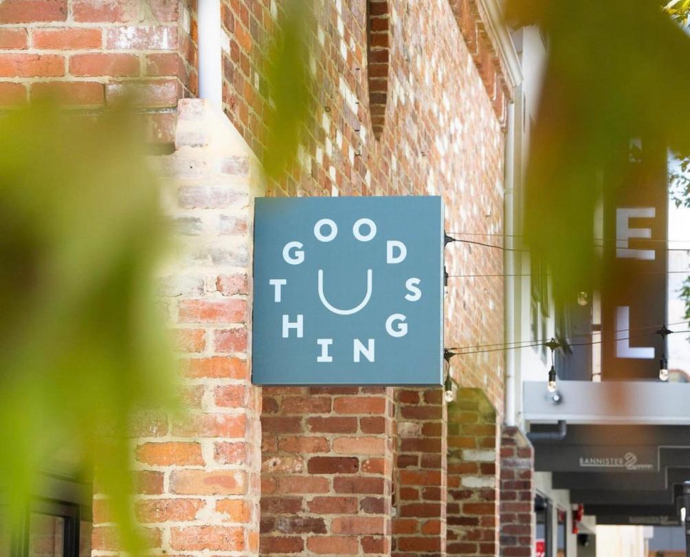 Good Things logo on a blue sign against the red bricks of the cafe