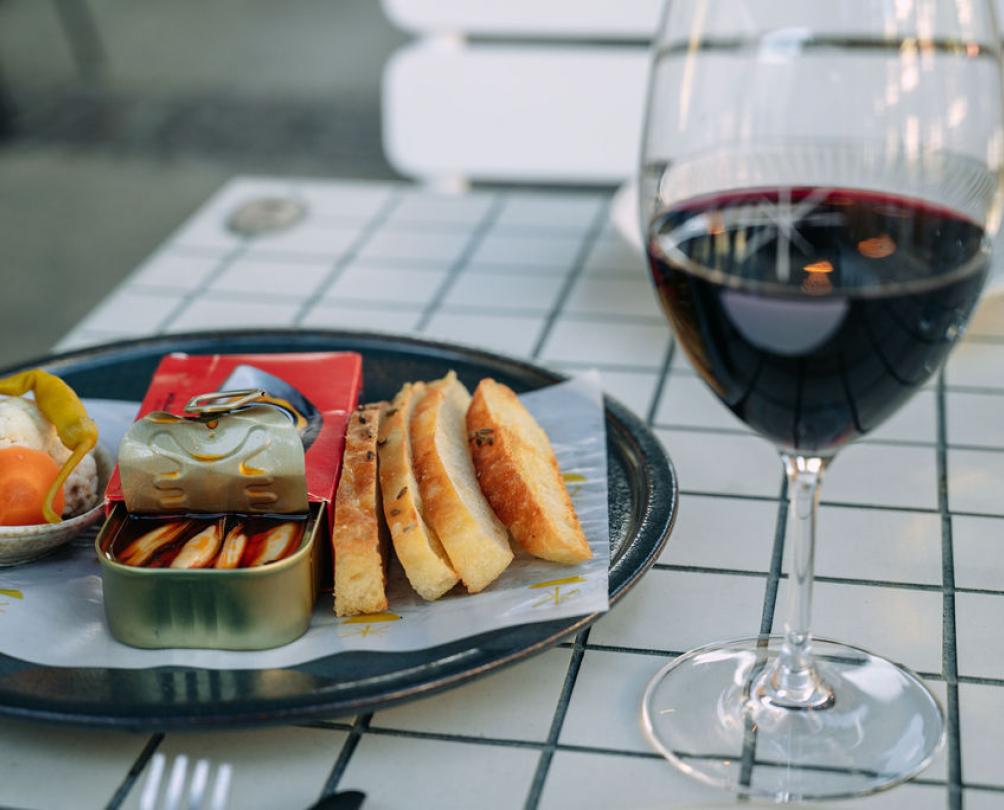 Glass of red wine next to a plate of sardines and pickled vegetables at Sailing for Oranges