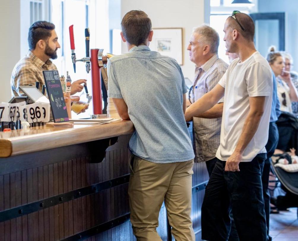 Three male guests and a bartender standing at the bar at The Wray Hotel 