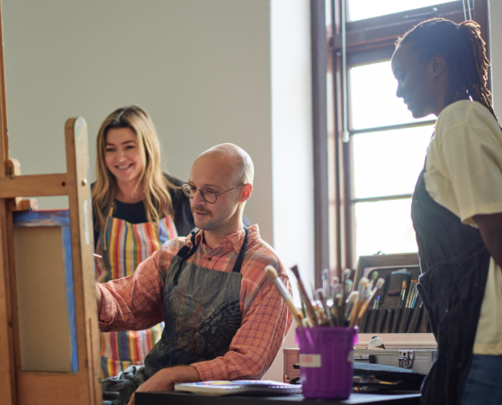 person paints at an easel in a light-filled, heritage room