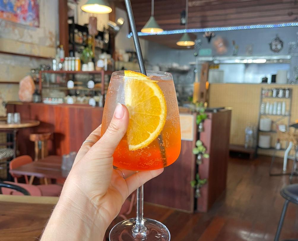 A hand holding a spritz cocktail.