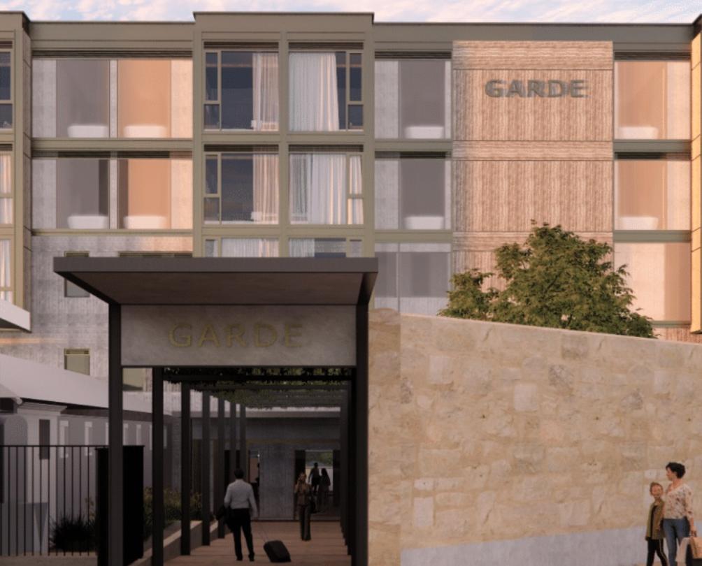 A detailed digital render showing the entrance to a three storey hotel at sunset. 