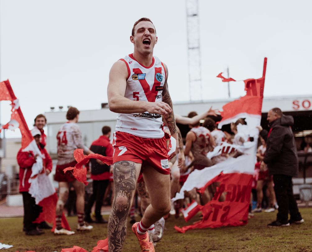 A man in a red and white football jersey celebrates after a win.