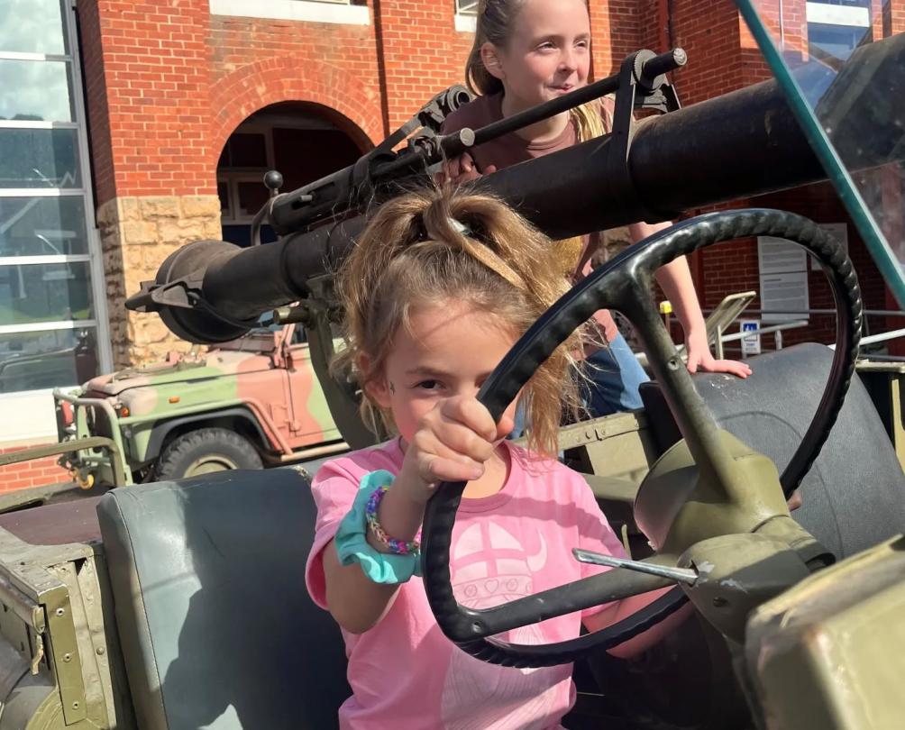 Two young girls playing in an old army jeep.
