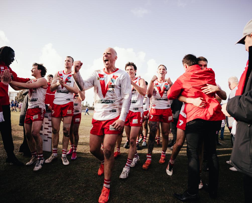 Men dressed in red and white football jerseys run off a field.