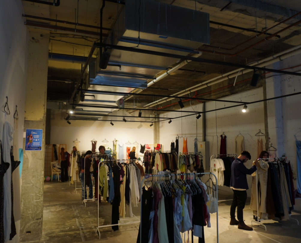 The interior a shop with several clothes racks and art on the walls.