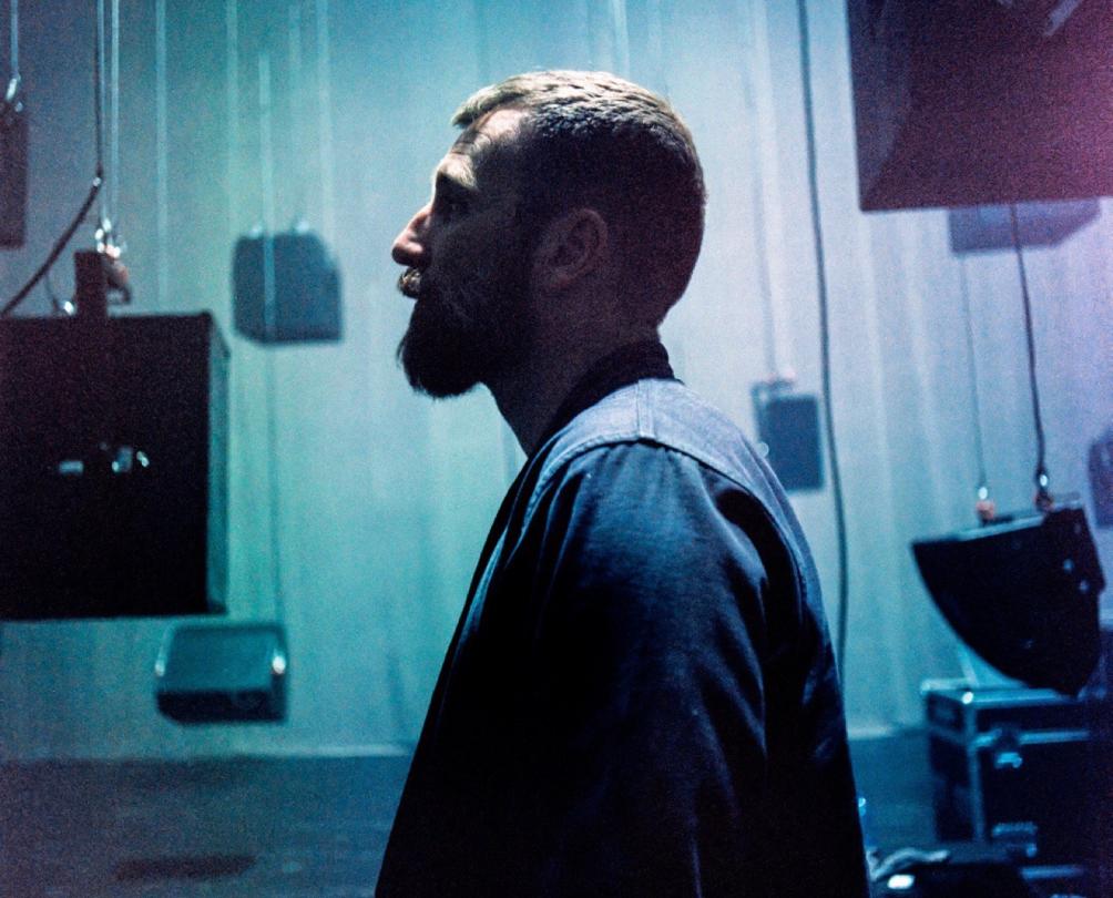 A man on side profile standing amongst black boxes