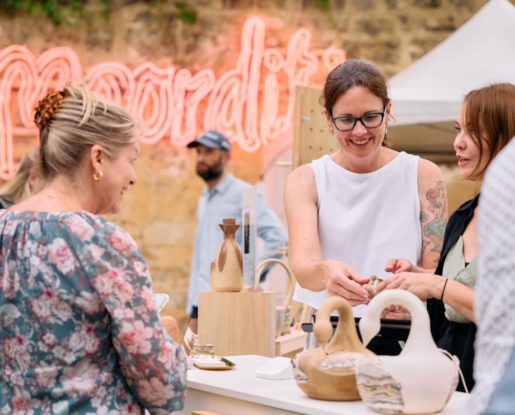 A woman purchases a handmade item from a stall.