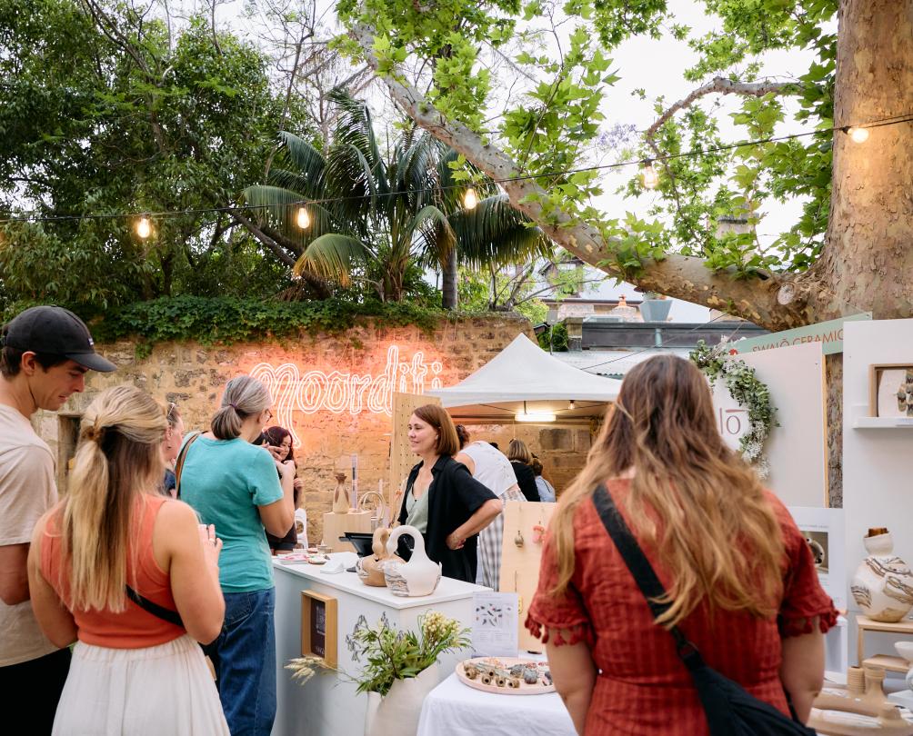 People admire a beautiful gift stall under a big tree.