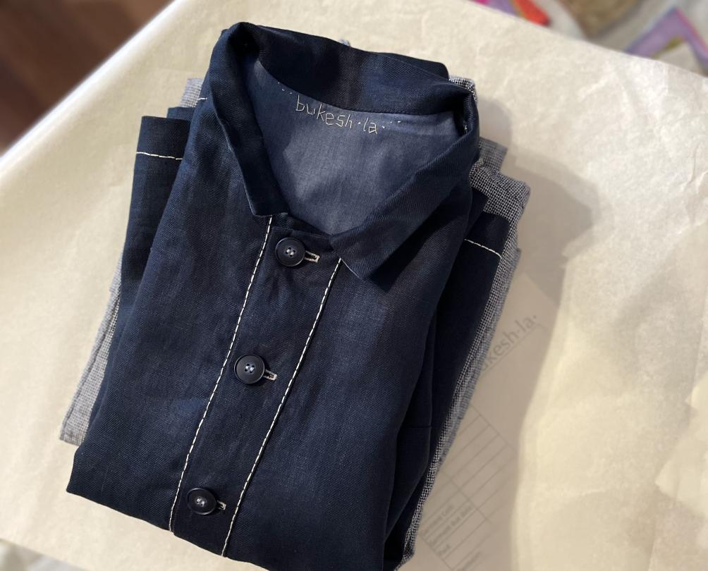 A folded denim button up shirt on wrapping paper on a glass table.