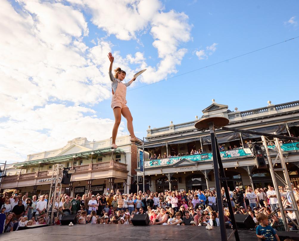 A woman walks on a tightrope in front of a huge crowd.