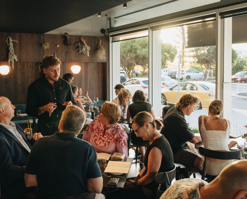 A full restaurant dining room with wooden walls and dark timber ceiling.