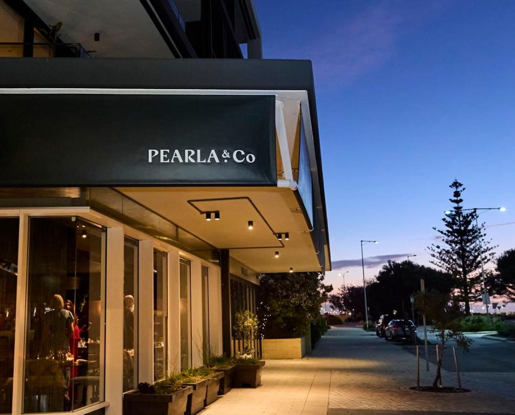 An exterior of a restaurant called Pearla & Co at dusk