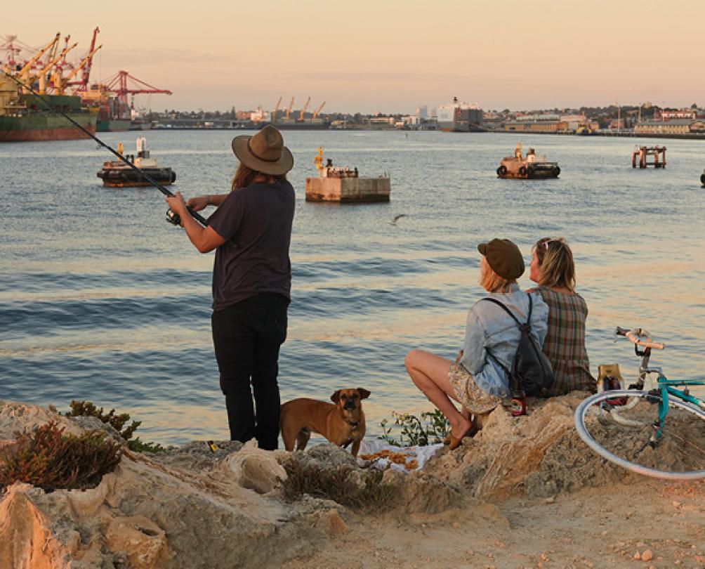 group of people fishing off a rock wall 