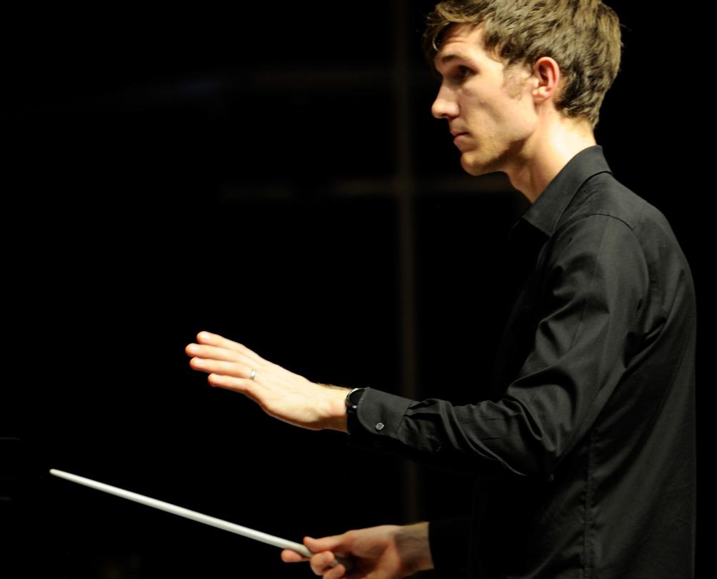 a man in a black suit being a conductor